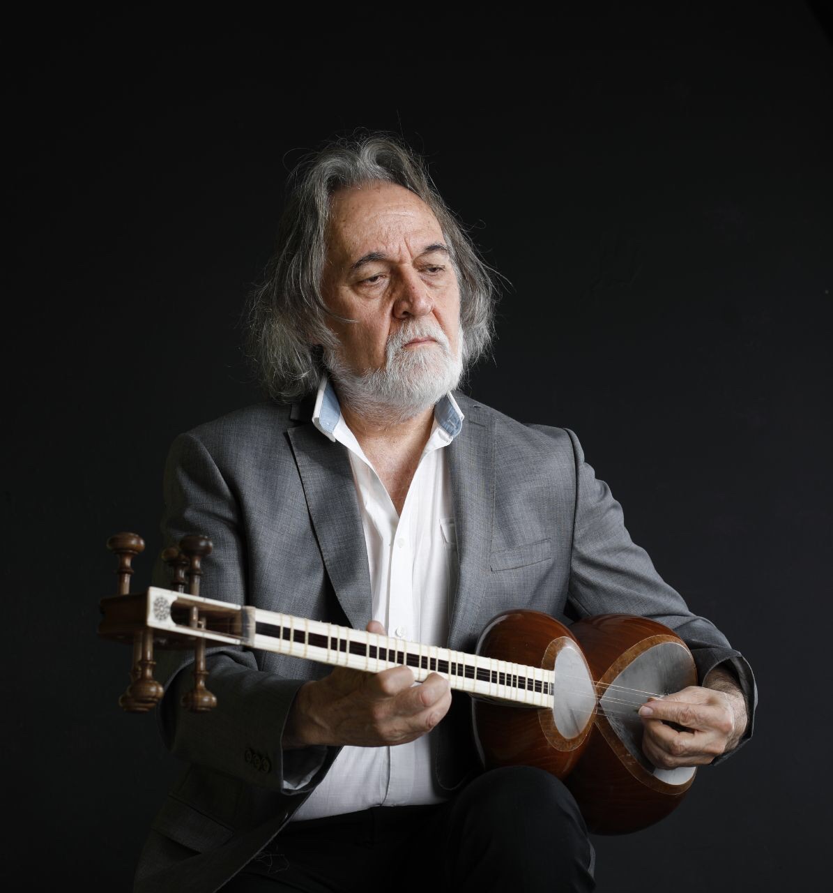A portrait of Majid Derakshani holding an Iranian string instrument known as the tar